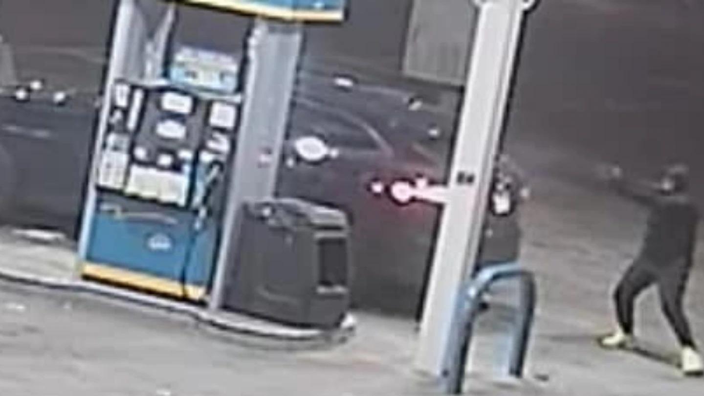 Ein Auto und ein Mann mit einer Pistole an einer Tankstelle