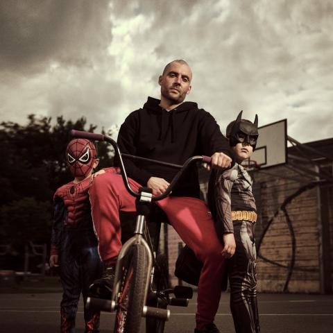 Shaban sitzt auf einem BMX.Neben ihm seine Söhne in einem Batman und Spiderman Kostüm
