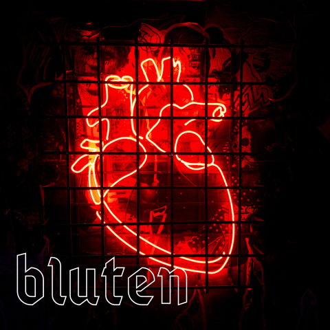 Ein Bleiglasfenster mit einem stilisiertem Herz. Neonrot auf schwarzem Hintergrund. Dazu das Wort Bluten.