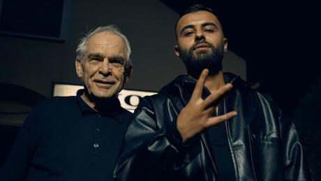Anonym macht ein Westside-Symbol und posiert mit einem alter Mann für die Kamera