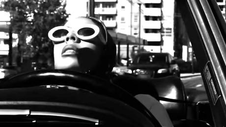 Eine Frau mit Kopftuch und Sonnenbrille in einem Auto in schwarzweiß