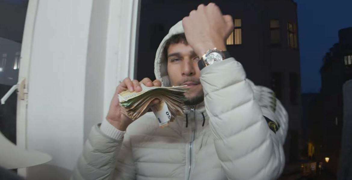 Lucio101 zeigt seine Uhr und sein Geld